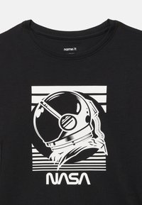 Czarna koszulka z białą grafiką hełmu astronauty i słowem "NASA" na tle poziomych pasków.