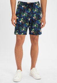 Costumi da bagno floreali con una base blu navy scuro, foglie verdi e fiori bianchi. Vita elastica con cordino nero. Eleganti ma funzionali.