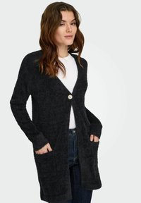 Cardigan gris foncé et pelucheux avec un col en V, un bouton décoratif unique et deux poches avant. Poignets et ourlet côtelés.