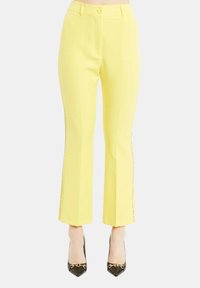 Pantaloni gialli su misura con gamba dritta e dettagli laterali discreti. Il tessuto ha una texture liscia e presenta una chiusura con bottone in vita.