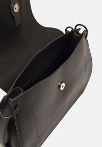 Borsa a tracolla nera in pelle con una texture liscia, dotata di chiusura a scatto magnetica e due anelli metallici per il fissaggio della tracolla. Tasche interne visibili.