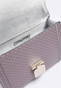 Paarse neplederen handtas met geometrisch reliëfpatroon, gouden sluiting en zilveren voering. Merkenlabel zichtbaar aan de binnenkant.
