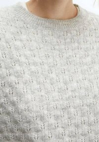 Pull gris clair avec un motif de tricot texturé mettant en avant de petites feuilles. Encolure ronde, matière douce et aspect douillet.