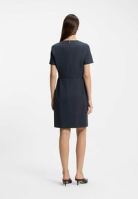 Navy short-sleeve dress with a structured fit, knee-length hem, back zipper, and smooth texture. Minimalist design with clean lines.
