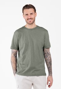 Olijfgroene katoenen t-shirt met een ronde hals, korte mouwen en een ontspannen pasvorm. Kenmerkt zich door subtiele textuur en stikseldetails.