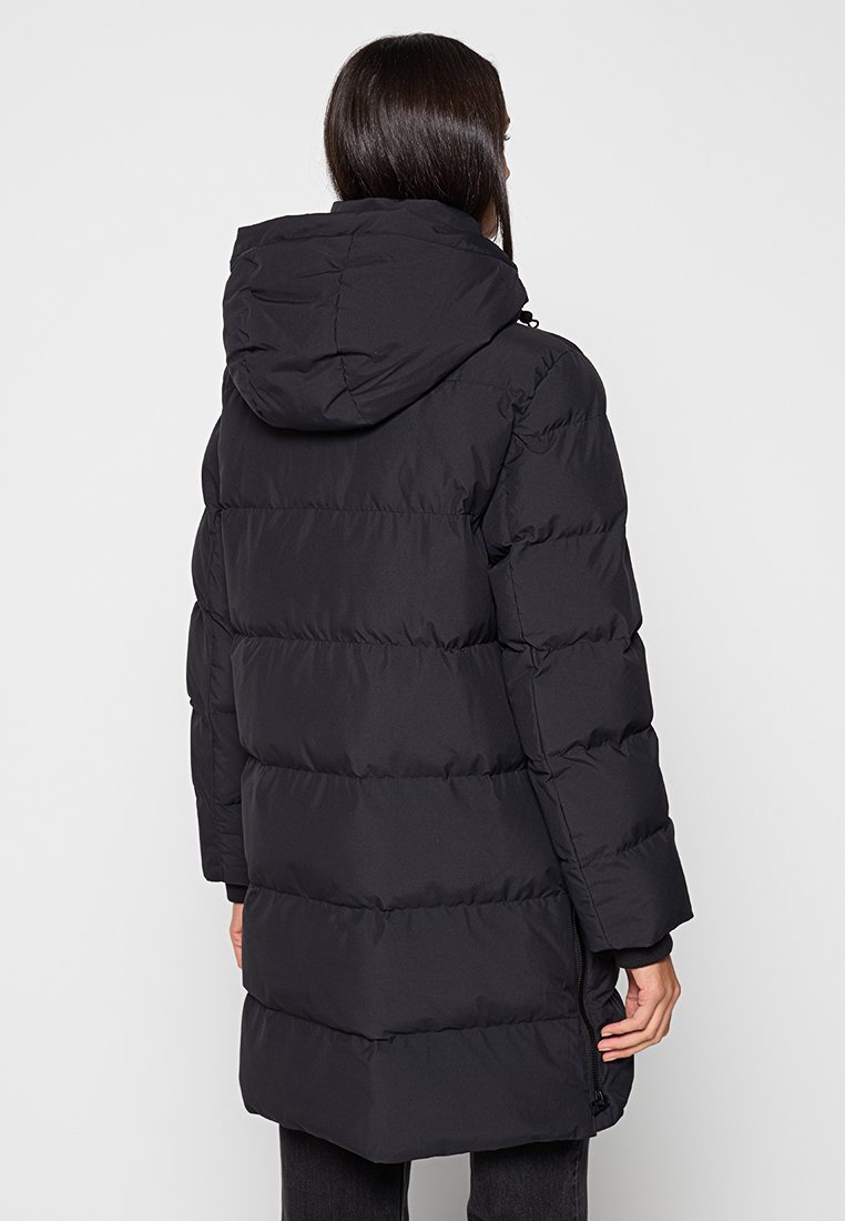 Schwarzer Steppmantel mit Kapuze, mit gesteppter Optik, langen Ärmeln und Seitentaschen. Glatte Textur mit mittellangem Schnitt.