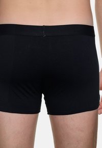 Boxer shorts neri in cotone con una texture liscia, dotati di una cintura morbida e senza motivi o accenti visibili.