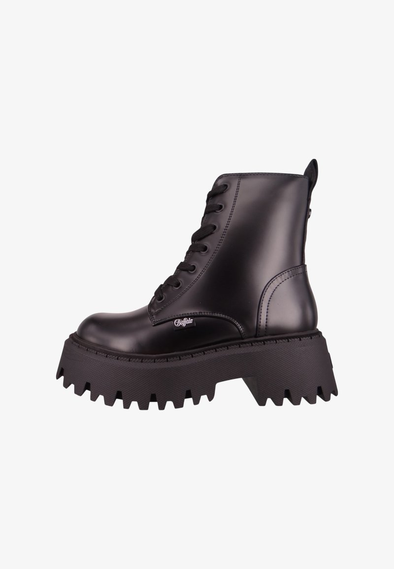 Bota de tornozelo de couro preto com sola de borracha robusta e ondulada, fecho de cadarço à frente e detalhe do logo na lateral. Textura suave e design robusto.