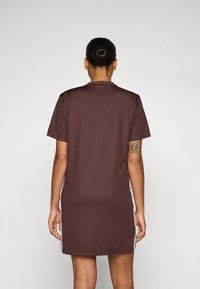 Brown short-sleeve dress with a straight cut, featuring white side stripes. Made from smooth fabric, with a crew neck and no visible fasteners.