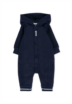 Combinaison intégrale bleu marine avec capuche, présentant une texture côtelée, un logo blanc sur le devant et des poignets rayés au niveau des chevilles.