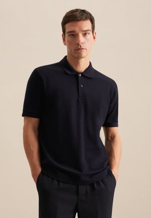 Marineblauwe polo-shirt gemaakt van zacht materiaal, met een klassieke kraag, korte mouwen en een knoopsluiting met drie knopen. Slim fit met minimale details.