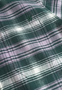 Green and lavender plaid fabric with a soft texture. Features a small embroidered logo and prominent horizontal and vertical lines.