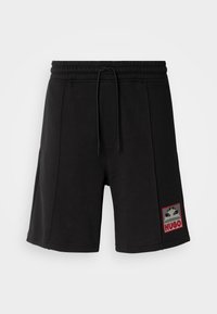 Shorts en coton noir avec une ceinture élastique, un cordon de serrage, des poches latérales et un écusson logo affichant "HUGO" en rouge et gris.