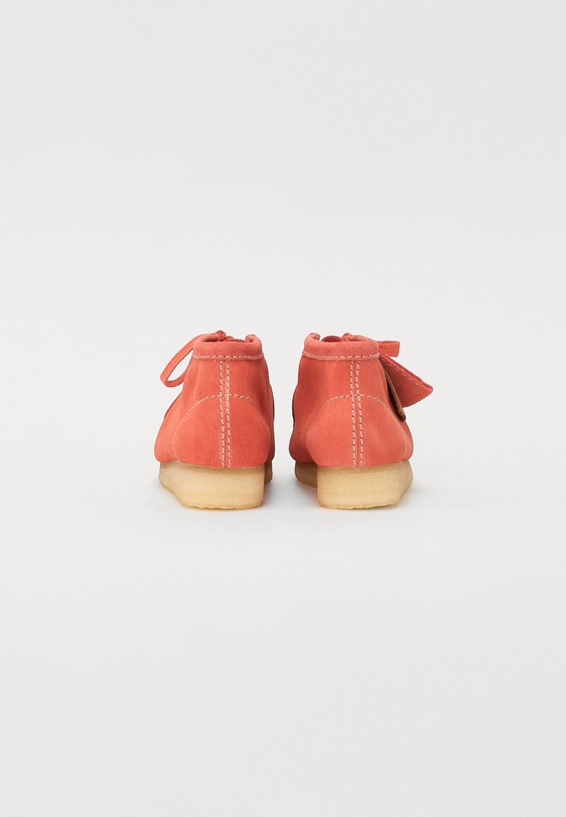 Botas de tobillo de ante coral con puntera redonda, cordones en la parte trasera y suela de goma ligera. Los detalles de costura añaden textura. Se muestra la vista trasera.