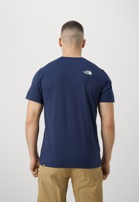 Navy blue cotton t-shirt with short sleeves, crew neck, and The North Face logo in white on the upper back. Smooth texture, standard fit.
