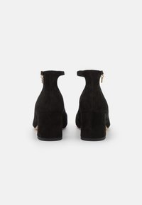 Botines de ante negros con tacón de bloque, detalle de cremallera y una textura suave, que presentan una silueta simple y elegante.