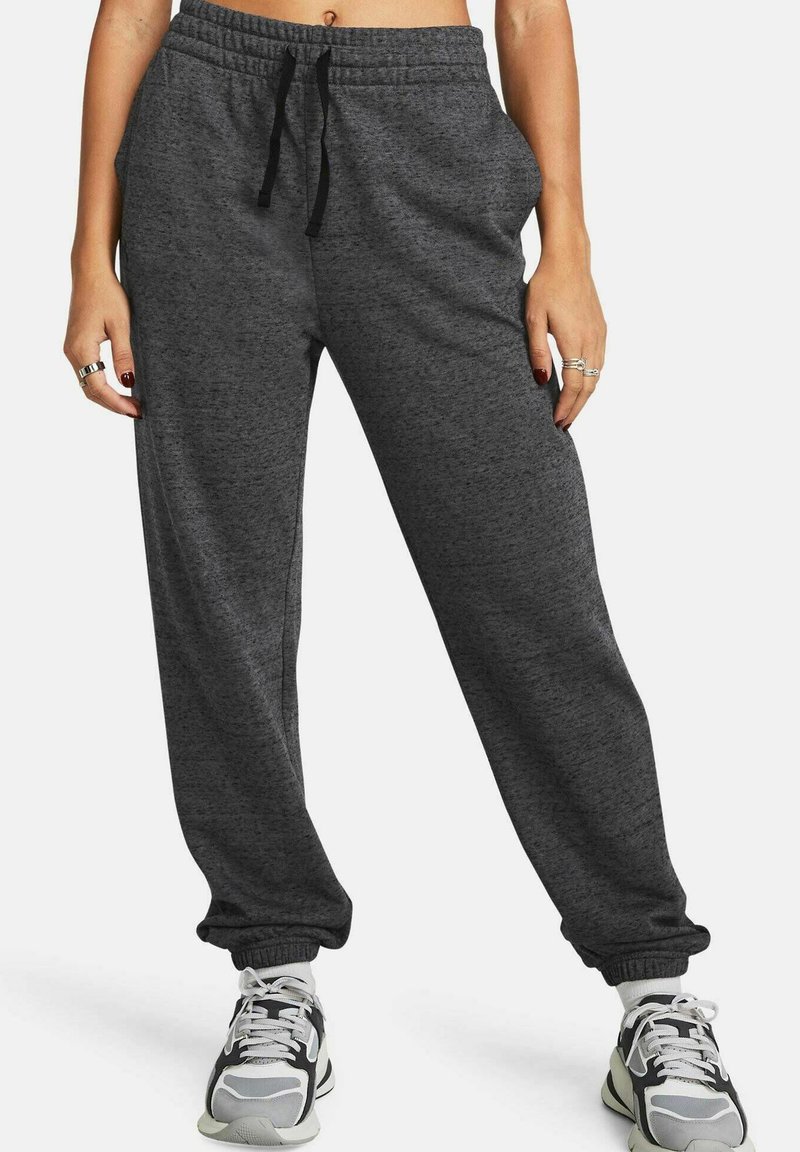 Graue Jogginghosen mit einem Kordelzugbund, schmal zulaufenden Knöcheln und einer weichen Textur. Kombiniert mit schwarz-weißen Turnschuhen.