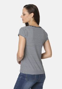 Camiseta de mangas cortas a rayas en azul marino y blanco, con cuello redondo y silueta ajustada, combinada con unos vaqueros de denim azul.