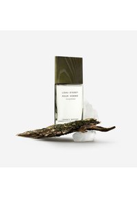 L'Eau d'Issey Pour Homme duftflaske med grønt trelokk, glasskropp og etikett på en teksturert trebase og is-lignende materiale.