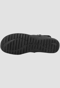 Sole di scarpa nera in gomma con motivo di battistrada profondo, caratterizzata da scanalature e prominenze per la trazione. Design piatto senza loghi o accenti visibili.