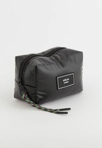 Czarny, pikowany worek z zaokrąglonym dnem, z zipem i kolorowym, plecionym uchwytem. Etykieta mówi "APRES SKI DOLOMITI."