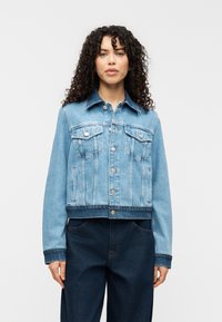 Ανοιχτό μπλε τζιν μπουφάν με κλείσιμο κουμπιών, δύο τσέπες στο στήθος και κοντή σχεδίαση. Διαθέτει κλασικό γιακά και αντίθετη ραφή.