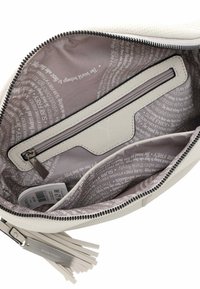 Interno di una borsa bianca testurizzata con una tasca con zip, foderato di grigio chiaro con testo ripetuto e un tirazip in frange beige.