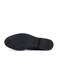 Black rubber sole of a dress shoe with deep treads and rectangular and cross-shaped patterns for grip.