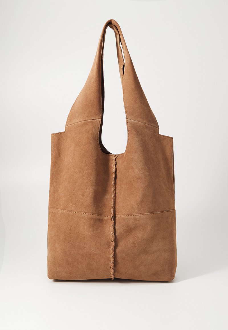 Bruine suede tote bag met twee brede handvaten, een uitsparingsopening en een centrale gevlochten detail, met een zachte textuur en een minimalistisch ontwerp.