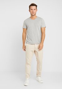 Gray v-neck t-shirt paired with beige chinos and white sneakers. The t-shirt has short sleeves and a soft texture. Simple design, minimal details.