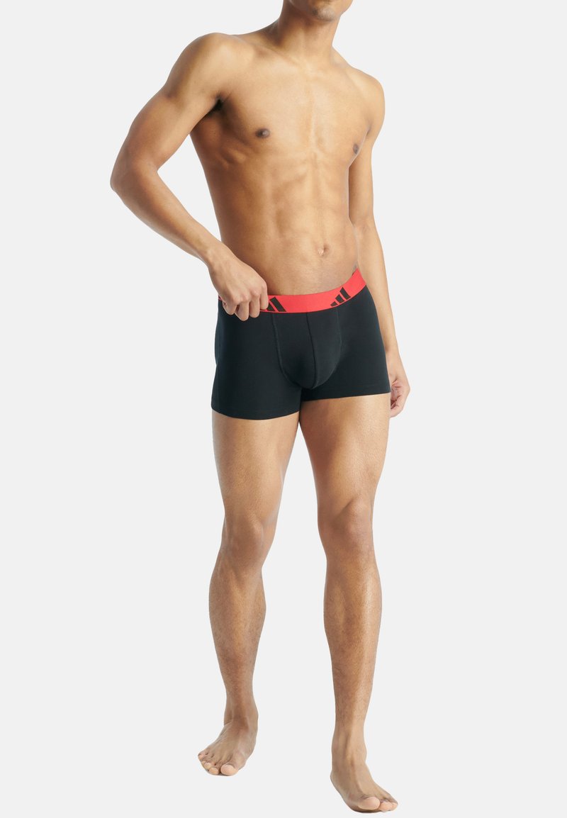 Μαύρα μποξεράκια με κόκκινη ελαστική μέση που έχει λογότυπο. Το ύφασμα φαίνεται λείο και εφαρμοστό, τονίζοντας το σχήμα και την άνεση.