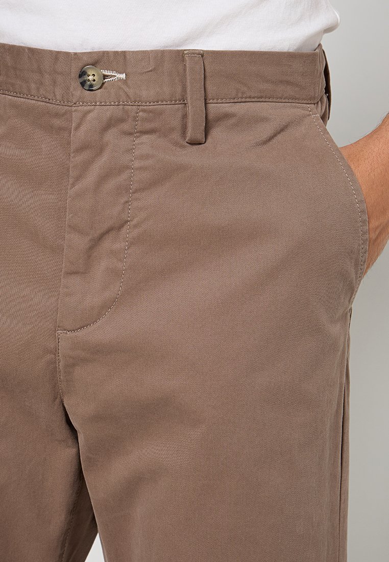 Braune Baumwollchinos mit glatter Textur, ausgestattet mit einer Vordertasche, Knopfverschluss und subtilen Stickdetails.