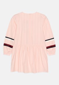 Vaaleanpunainen pitkähihainen mekko, jossa on kokoontuva vyötärö. Mekossa on raitayksityiskohtia tummansinisinä, valkoisina ja burgundina hihoissa sekä takana vetoketju.