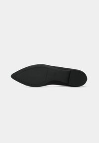 Black pointed-toe shoe with a smooth upper texture, flat heel, and rubber sole featuring a simple design with no embellishments.