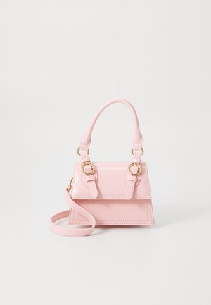 Mała różowa torebka z górnym uchwytem, złotymi akcentami na klamrach oraz regulowanym paskiem na ramię na białym tle.