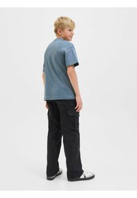 T-shirt en coton bleu décontracté à manches courtes, associé à un pantalon cargo noir avec poches latérales et une coupe droite.