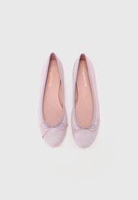 Sapatilhas de balé lilás com um acabamento suave em camurça, bico arredondado, detalhe de laço discreto e interior suave rosa. Contorno exterior em lilás correspondente.