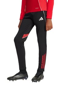 Schwarze Sporthosen mit roten Akzentpaneelen, drei roten Streifen am Unterschenkel und einem auffälligen weißen Adidas-Logo.