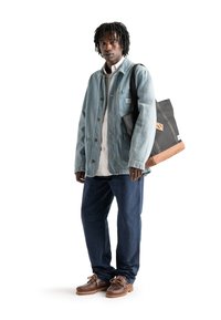 Jeansjacka i ljusblå, vit skjorta med knappar, mörkblå byxor, bruna skor och en svart tygväska med beiga detaljer.