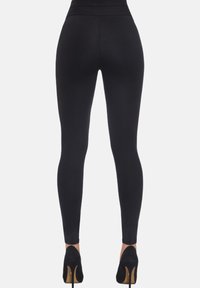 Czarne legginsy z elastycznego materiału, z wysokim stanem i dopasowanym krojem, zestawione z czarnymi butami na wysokim obcasie.