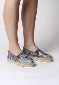 Sive zmijske espadrile na špic z pletenim jutenim podplatom, elastičnimi stranskimi pannami in strukturno zgornjim delom. Raven, sproščen dizajn.