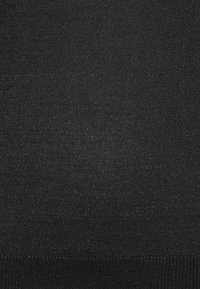 Svart stickad tyg med en slät textur och subtil lyster. Har en ribbad nederkant och jämnt fördelade stygn genom hela tyget.