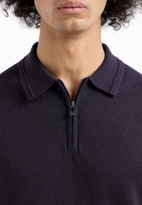 Marineblauw polo shirt met ritssluiting, gemaakt van een zachte gebreide stof, met een kraag en een ritssluiting van kwartlengte met een metalen trekhaak.
