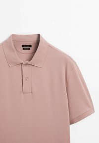 Polo en mauve clair, en coton texturé. Doté d'un col classique, d'une patte de boutonnage à deux boutons, de manches courtes et d'un ourlet droit.