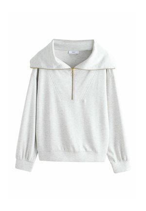 Gaiši pelēks pulovers ar lielu apkakli, ceturtdaļas rāvējslēdzēja priekšpusi, ribveida aprocēm un mīkstu kokvilnas maisījuma audumu. Aprīkots ar diagonālām šuvju detaļām.