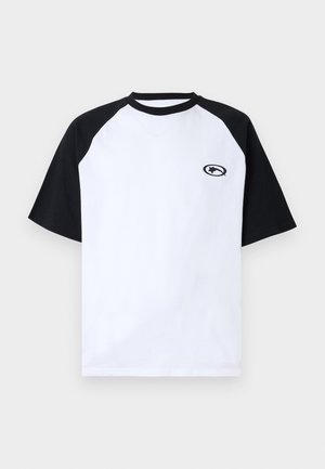 Koszulka z krótkim rękawem z białym korpusem, czarnymi rękawami raglanowymi, czarnym okrągłym dekoltem oraz małym czarnym logo gwiazdy w owalnym kształcie na lewej piersi.