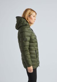 Doudoune verte olive avec capuche, poches latérales zippées et un accent noir sur le devant. Présente une texture matelassée et un matériau imperméable.