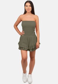 Olijfgroene strapless jumpsuit met een gerimpelde bovenkant en een gerimpelde zoom. In combinatie met witte sneakers, heeft het een gestructureerde stof.