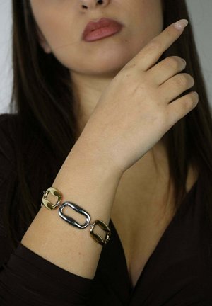 Bracelet chaîne en or et argent avec maillons allongés de formes alternées, présentant une finition lisse et brillante ainsi qu'un fermoir sécurisé.