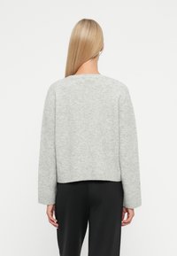 Svijetlosivi pleteni pulover s okruglim izrezom, skraćenog dizajna i dugim rukavima. Završava s rebrastim manžetama i rubom za dodatnu teksturu.